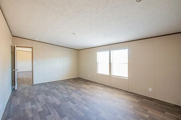 a view of an empty room with wooden floor and window
