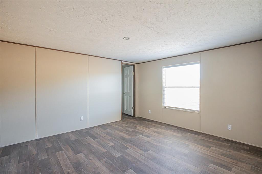 245 Lelon Lane Springtown, TX 76082 - Photo 25 of 37 an empty room with wooden floor and windows with curtains