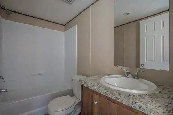 a bathroom with a granite countertop sink toilet and a mirror