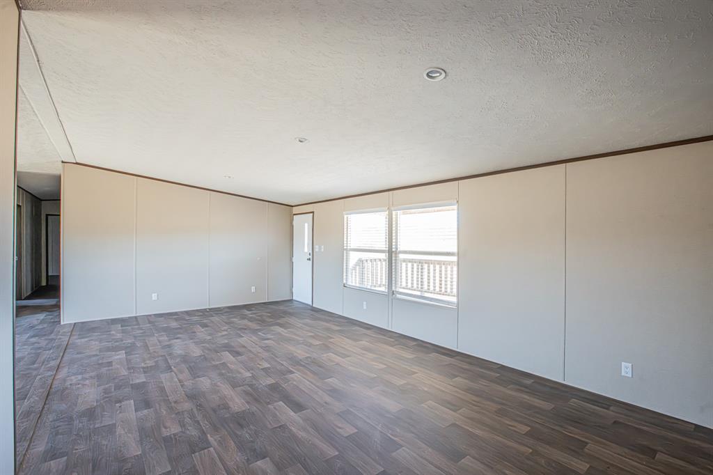 245 Lelon Lane Springtown, TX 76082 - Photo 6 of 37 a view of an empty room with wooden floor and a window