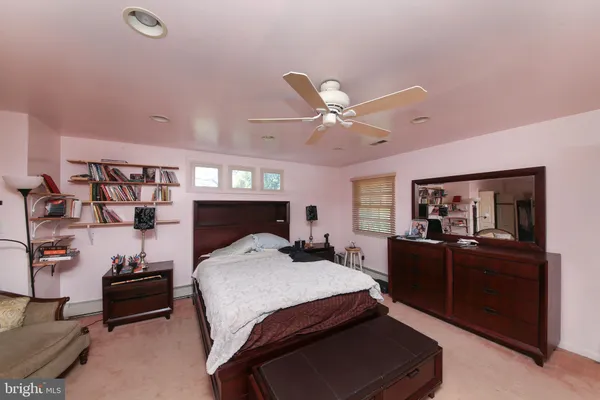 a bedroom with a bed a dresser and potted plant