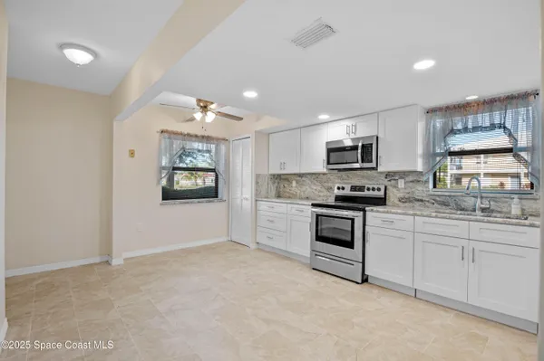 a kitchen with granite countertop white cabinets and stainless steel appliances