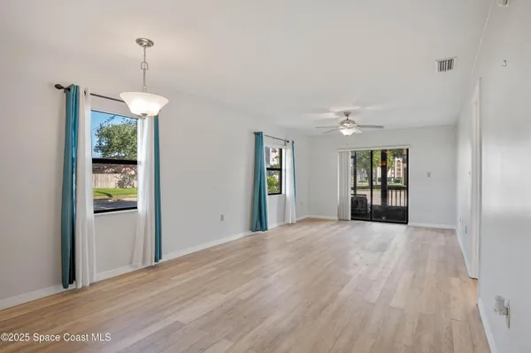 a view of an empty room with window and wooden floor