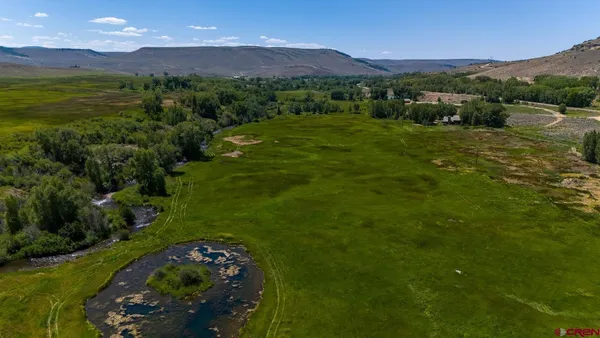 a view of a lush green outdoor space with a swimming pool and valleys in the background