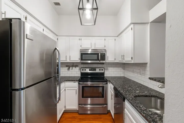 a kitchen with stainless steel appliances granite countertop a refrigerator a stove and a sink