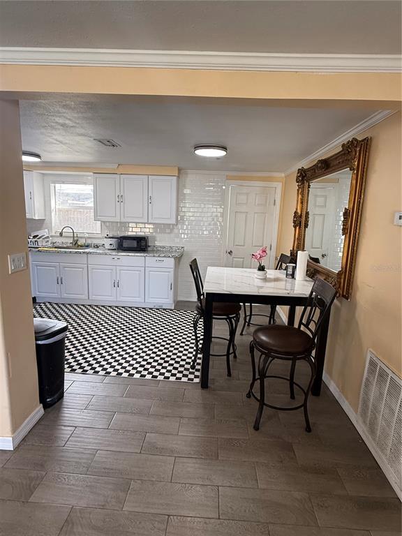 4550 Abdella Lane Holiday, FL 34690 - Photo 18 of 41 a kitchen with a dining table chairs and white cabinets