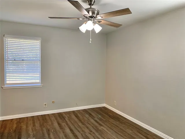 an empty room with a window and a chandelier fan