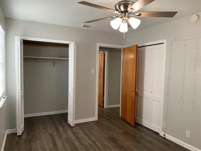 an empty room with wooden floor closet fan and windows