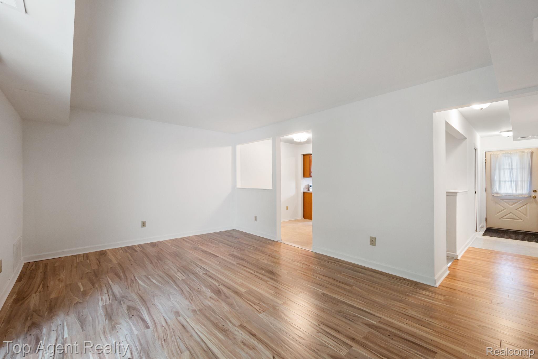 23420 Middlebelt Road Farmington, MI 48336 - Photo 7 of 32 Expansive room featuring wood-finish flooring, white walls, and a visible doorway to an additional area
