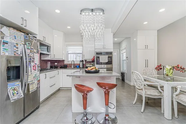 a kitchen with stainless steel appliances kitchen island granite countertop a refrigerator and a stove top oven