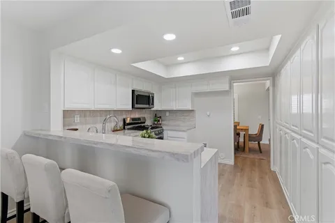 a kitchen with stainless steel appliances a sink a stove a refrigerator cabinets and living room view