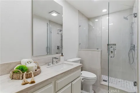 a bathroom with a granite countertop sink a toilet and shower