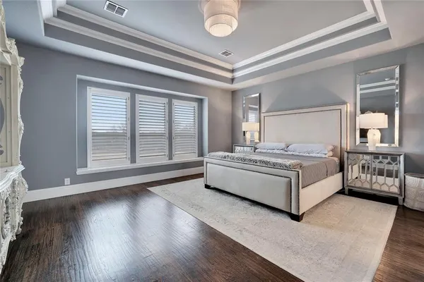 a spacious bedroom with a bed and a large window with wooden floor