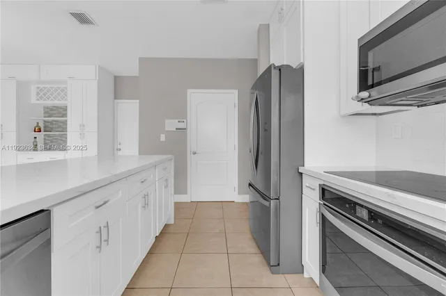 a kitchen with granite countertop a refrigerator and a stove top oven