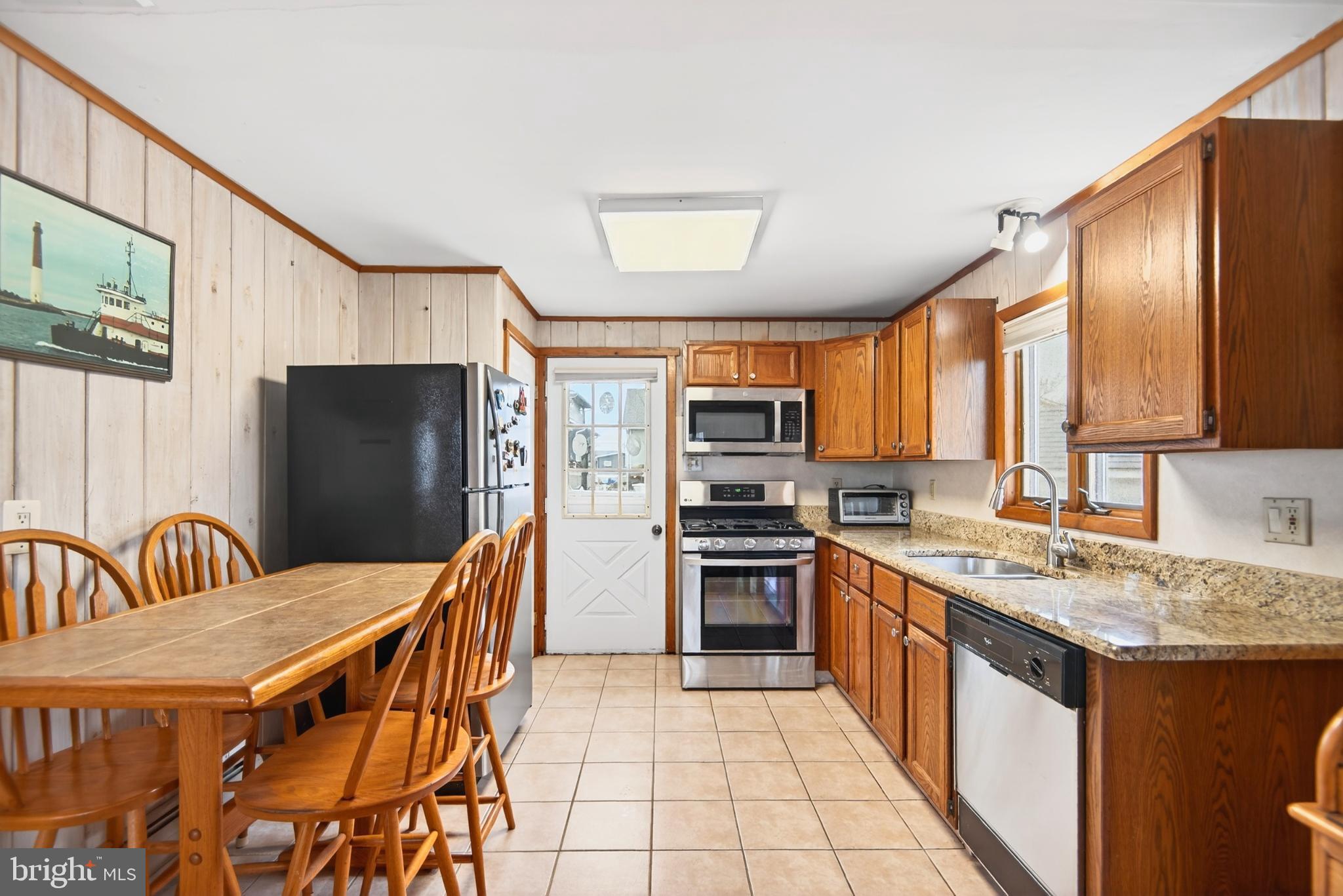 4 Rona Lane Manahawkin, NJ 08050 - Photo 11 of 28 a kitchen with stainless steel appliances granite countertop a sink a stove a refrigerator with a dining table and chairs