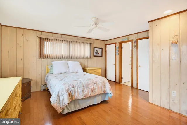 a bedroom with a bed and a dresser with wooden floor