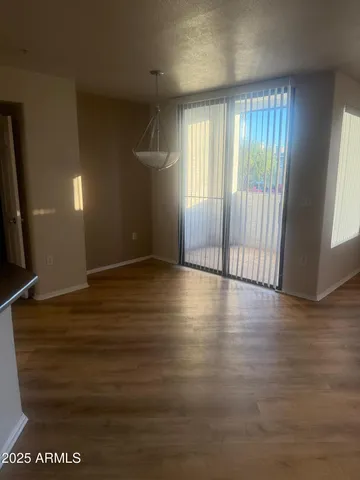 an empty room with wooden floor and windows with curtains