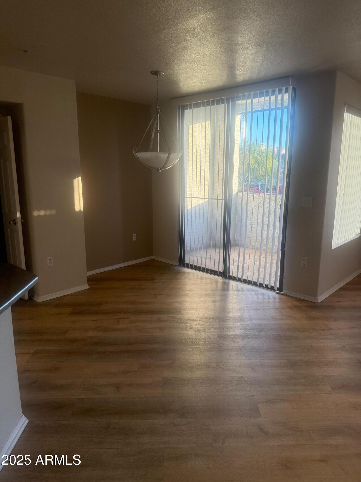 3848 North 3rd Avenue, Unit 2071 Phoenix, AZ 85013 - Photo 17 of 31 an empty room with wooden floor and windows with curtains
