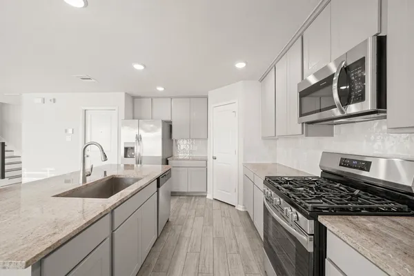 a kitchen with stainless steel appliances granite countertop a sink stove refrigerator and cabinets