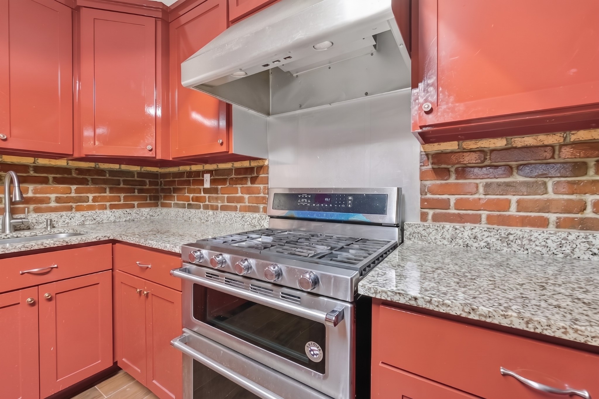 6014 Linda Drive Rosharon, TX 77583 - Photo 12 of 22 A close-up view highlights the durable stone work surfaces and the professional-grade double-oven gas range set against a classic masonry wall.