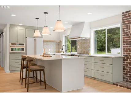 a kitchen with stainless steel appliances kitchen island granite countertop a table chairs and a sink