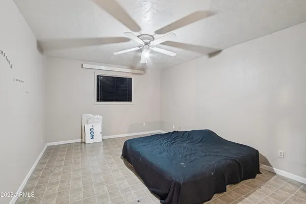 a bedroom with a large bed and a chandelier fan