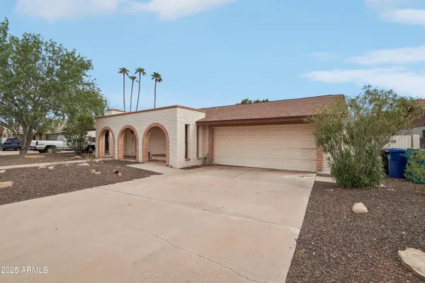 a view of a grey house with a yard and garage