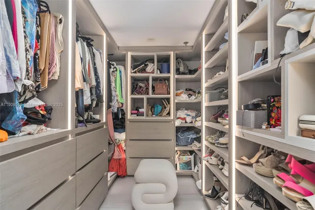 a view of walk in closet with clothes and shoes