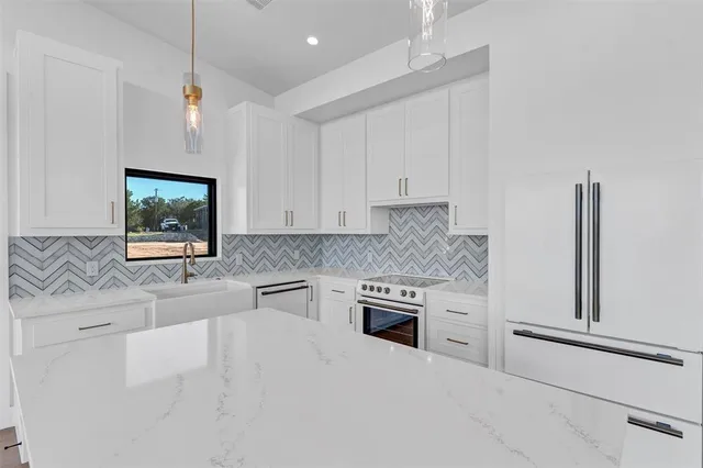 a large kitchen with stainless steel appliances a large counter top a stove a sink and a refrigerator