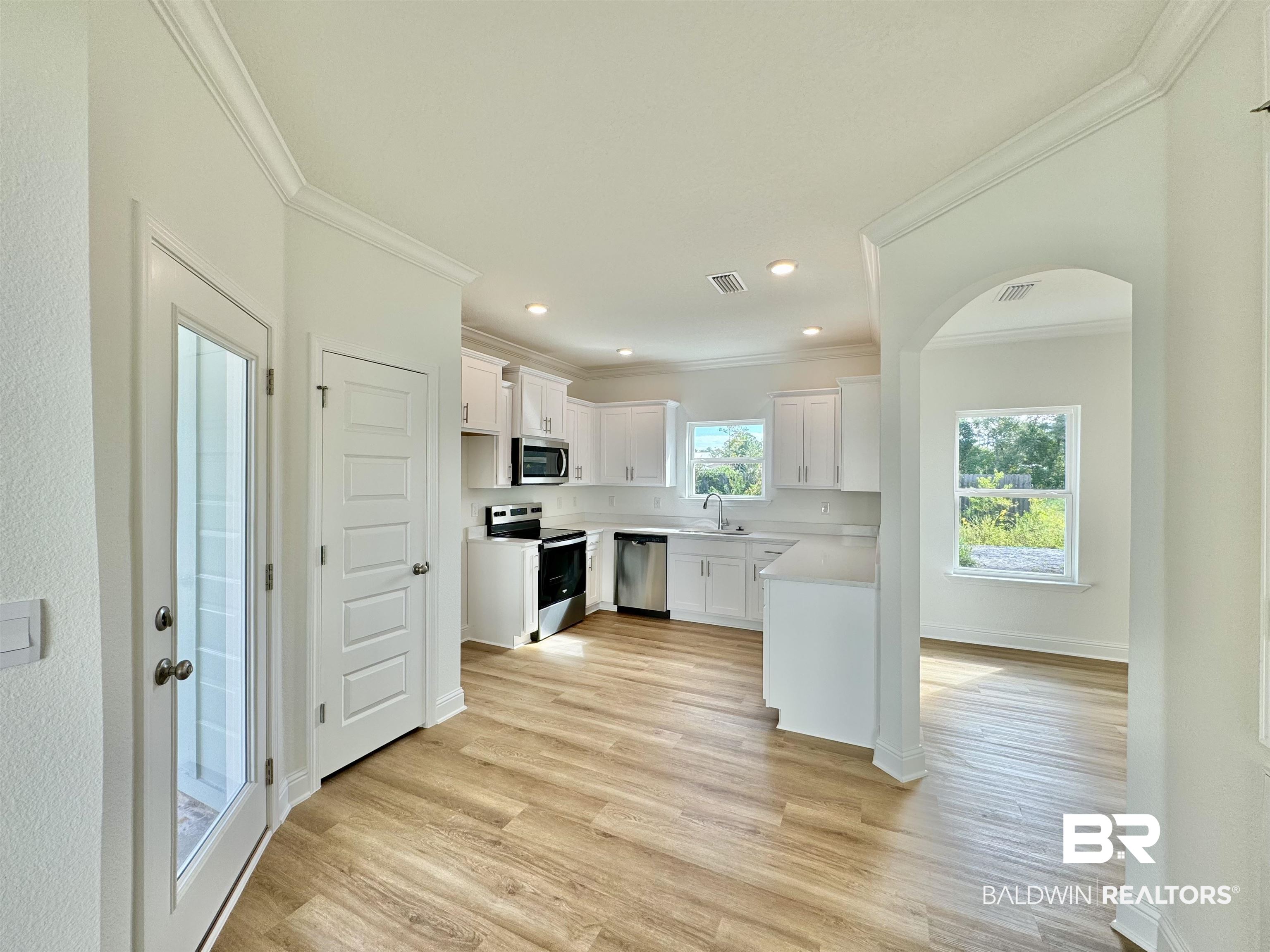 27491 Canal Road Orange Beach, AL 36561 - Photo 12 of 20 Kitchen featuring white cabinets, ornamental molding, sink, appliances with stainless steel finishes, and light wood-type flooring