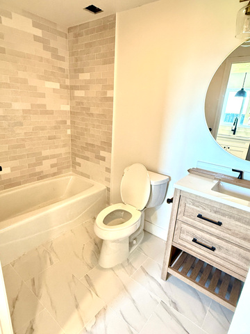 10158 High Point Lane Sandy, UT 84092 - Photo 18 of 24 Bathtub with subway tile surround, sleek white toilet, and wood-finish vanity with built-in shelving