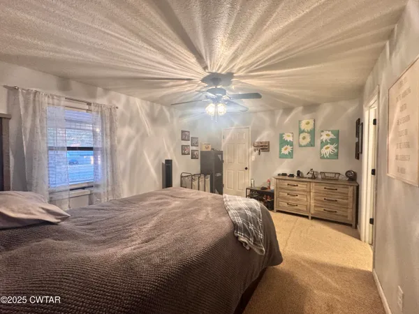 a spacious bedroom with a bed and ceiling fan