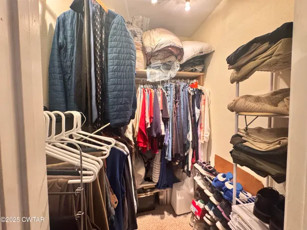 a view of walk in closet with clothes and shoes