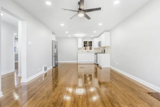 a view of empty room with wooden floor and fan
