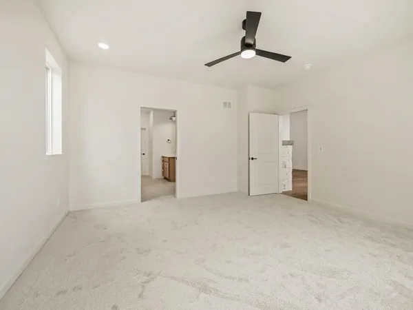 a view of an empty room with chandelier fan