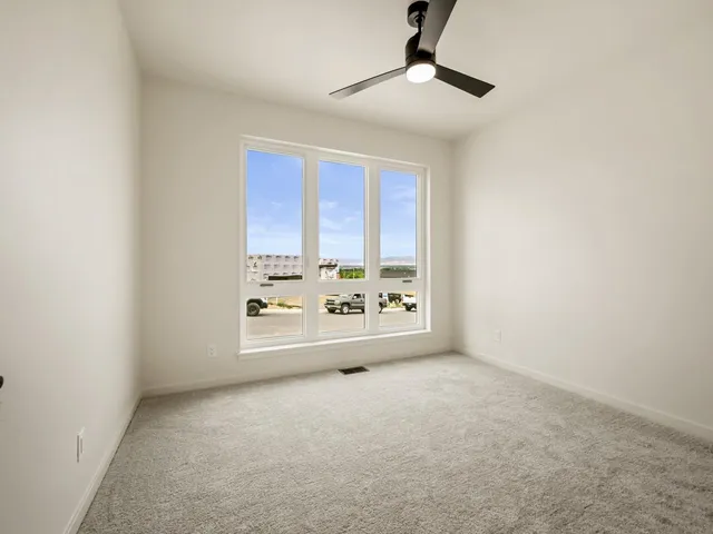 an empty room with a ceiling fan and windows