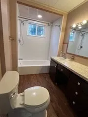 a bathroom with a granite countertop sink toilet a mirror and bathtub