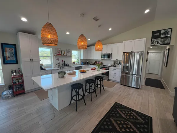 a kitchen with stainless steel appliances a dining table chairs stove refrigerator and cabinets