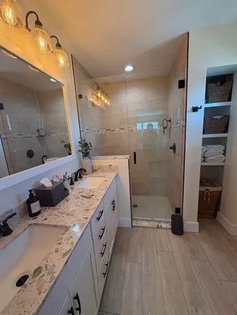 a bathroom with a double vanity sink a large mirror and shower