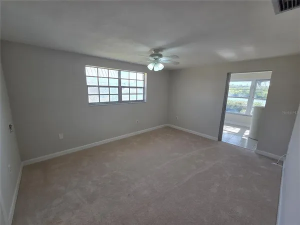 an empty room with windows and fan