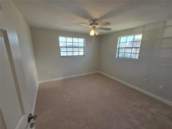 an empty room with windows and chandelier fan