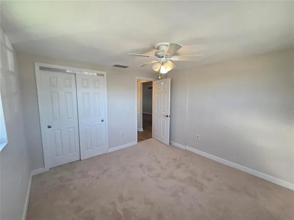 a view of an empty room with a chandelier fan