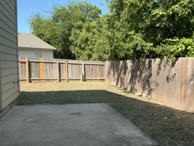 a view of backyard of white house with wooden fence