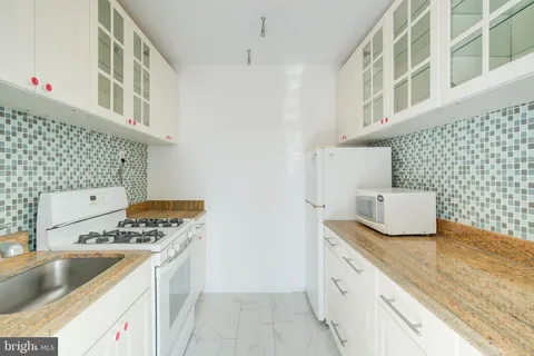 a kitchen with granite countertop white cabinets and a stove
