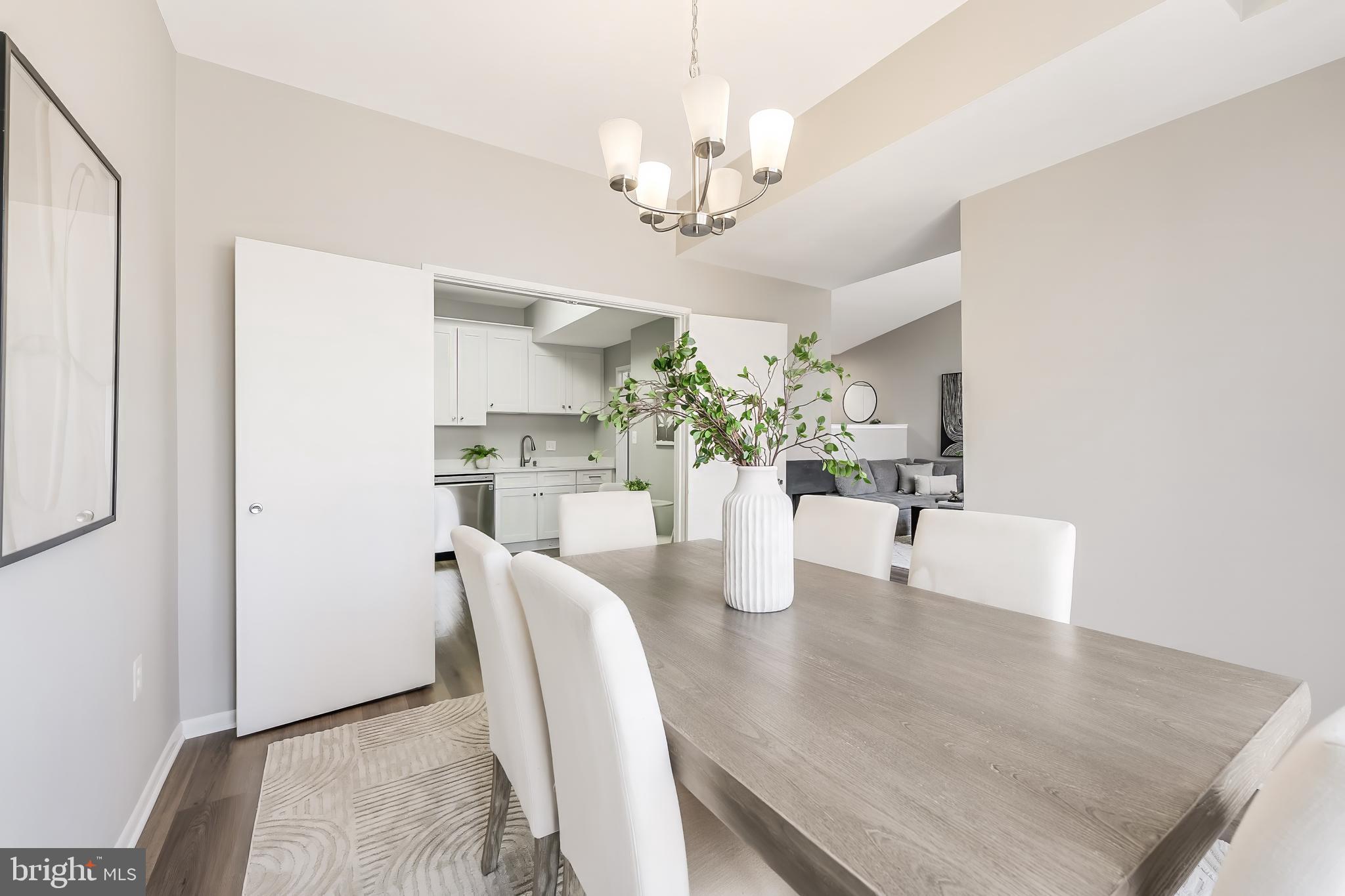 11564 Rolling Green Court, Unit 12/301B Reston, VA 20191 - Photo 11 of 31 a dining room with wooden floor a chandelier a glass table and chairs