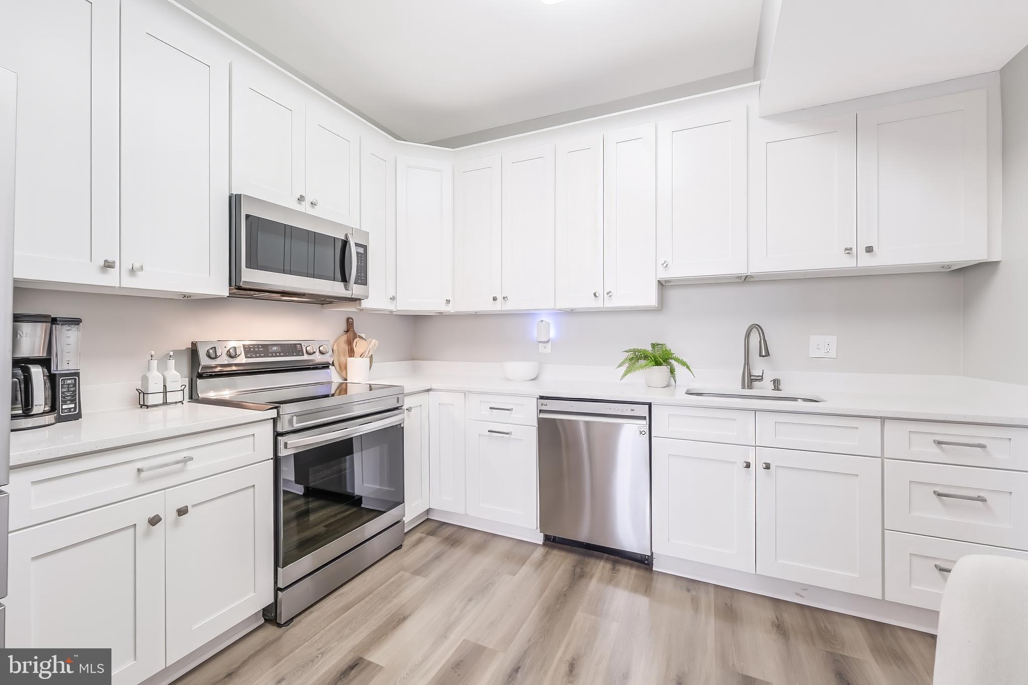 11564 Rolling Green Court, Unit 12/301B Reston, VA 20191 - Photo 4 of 31 a kitchen with granite countertop white cabinets sink and stainless steel appliances
