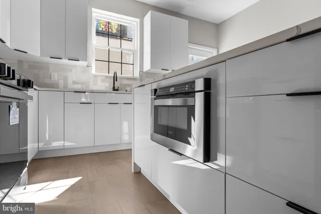 a kitchen with stainless steel appliances granite countertop a refrigerator a sink dishwasher a oven and white cabinets with wooden floor