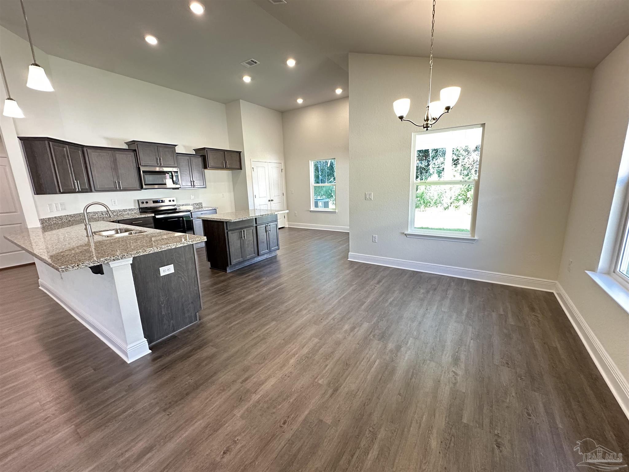 5451 Cherub Circle Milton, FL 32583 - Photo 5 of 13 a kitchen with stainless steel appliances kitchen island wooden floors wooden cabinets and window