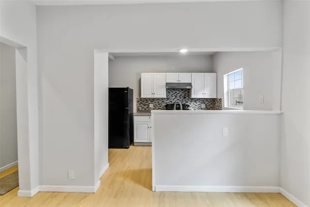 a kitchen with white cabinets and black appliances