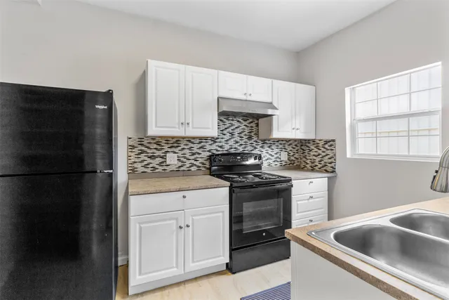 a kitchen with granite countertop white cabinets sink and stainless steel appliances